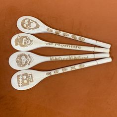 four wooden spoons with different designs on them sitting next to each other in front of a brown surface