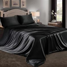 a bed with black sheets and pillows in a room