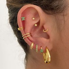 a woman wearing gold ear cuffs and piercings