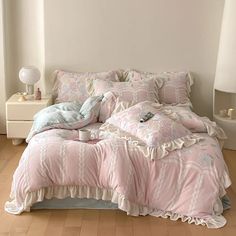 a bed with pink comforter and pillows in a room