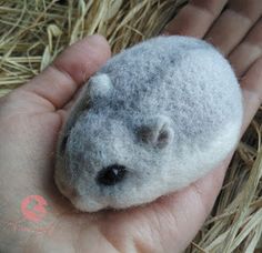 a hand holding a small stuffed animal in it's right hand on some hay