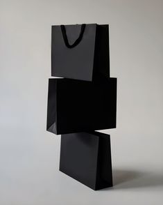 a black shopping bag sitting on top of a white table next to a gray wall