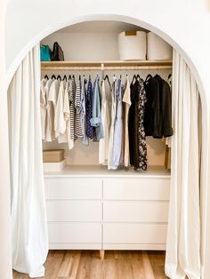 an open closet with clothes hanging on the wall and white curtains in front of it