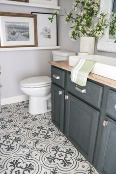 a white toilet sitting in a bathroom next to a sink under a framed picture on the wall