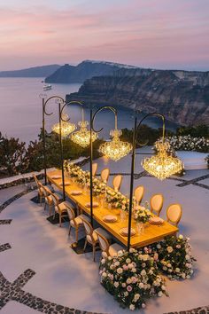 an outdoor dining table set up with chandeliers and flowers