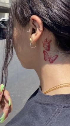 a woman with a butterfly tattoo on her left side of her neck and behind her ear