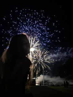 a woman standing in front of fireworks at night