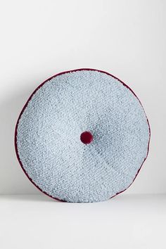 a white and red pillow on top of a white surface with a hole in the middle