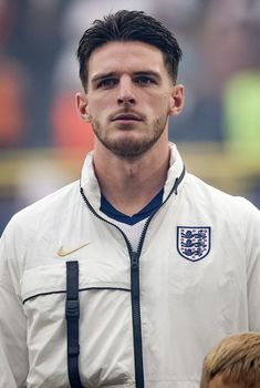 a man with a white jacket and black suspenders standing in front of a crowd