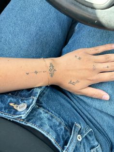 a woman's arm and hand with tattoos on it, sitting in a car