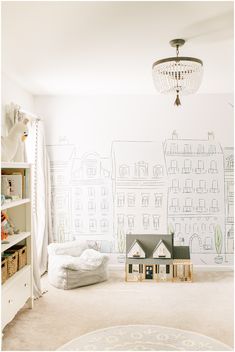 a child's room with a wall drawing on the wall and a toy house next to it