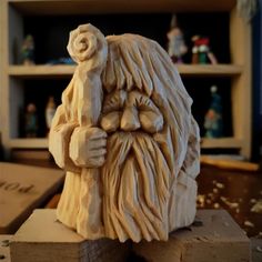 a wooden carving of an old man with a beard and long hair sitting on top of a piece of wood