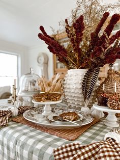 a table topped with plates and bowls filled with food next to a vase full of flowers