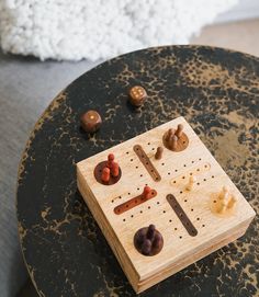 a wooden board game sitting on top of a table next to buttons and pegs