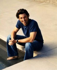 a man sitting on the edge of a pool smiling