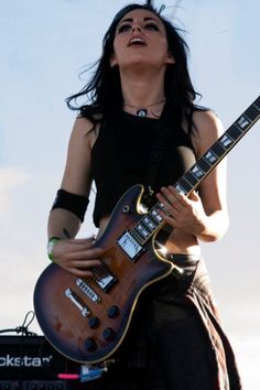 a woman playing an electric guitar on stage