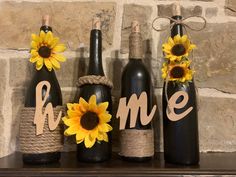 three wine bottles decorated with sunflowers and the word home are sitting on a mantle