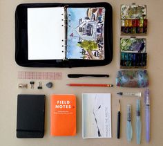 the contents of an art journal laid out on a table with pens, markers and pencils