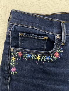 a pair of jeans with embroidered flowers on them