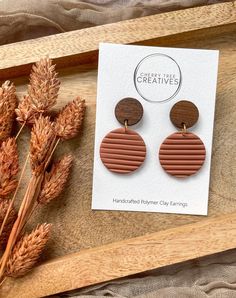 a pair of wooden earrings sitting on top of a table next to some dried flowers