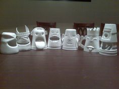 a group of white vases sitting on top of a wooden table next to each other