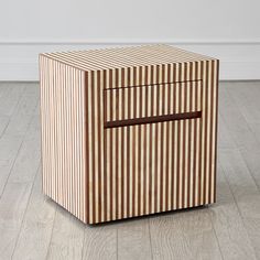 a small wooden box sitting on top of a hard wood floor next to a white wall