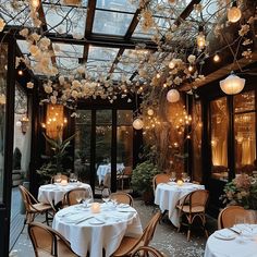 an outdoor dining area with tables, chairs and chandeliers hanging from the ceiling