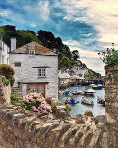 boats are parked in the water next to some buildings and flowers on a rock wall