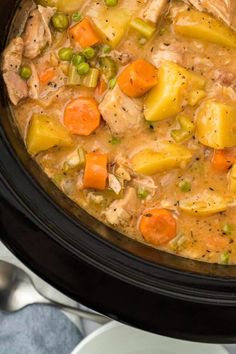 a crock pot filled with chicken, potatoes and carrots