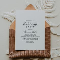 the wedding party is set up on top of a woven envelope with a white card