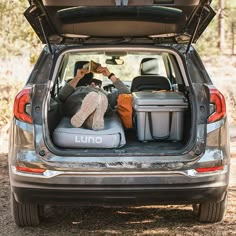 a person sitting in the back of a car with luggage on it's trunk