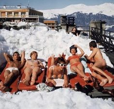 four people are lounging in the snow on their rafts and one person is taking a selfie