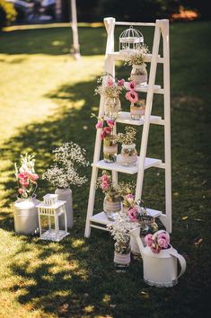 an outdoor wedding ceremony setup with flowers and birdcages on the side of a ladder