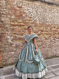 a woman in a blue dress standing next to a brick wall