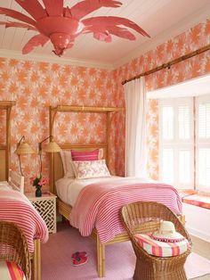 two beds in a room with pink and orange wallpaper