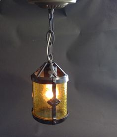 an old fashioned light hanging from a ceiling fixture with a chain attached to the side