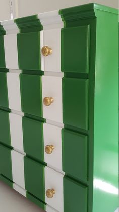 a green and white dresser with gold handles