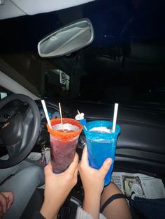 two people holding drinks in their hands while sitting in the back seat of a car