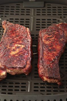 two steaks are being grilled on the grill