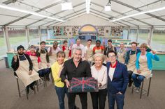 a group of people standing around each other in front of a table with a cake on it