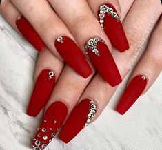 a woman's hand with red nail polish and diamond decorations on it, holding onto her nails