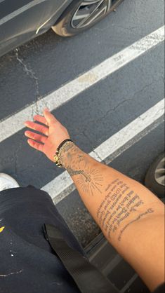 a person holding their hand out in the street with his arm tattoo on top of him