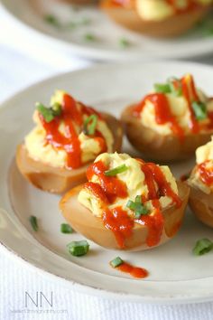 small appetizers are sitting on a plate with ketchup and green onions