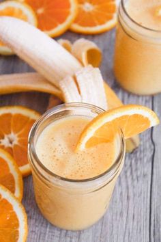 two glasses filled with orange smoothie next to sliced oranges