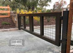 a wooden fence with metal bars on the top and bottom, in front of a garden area