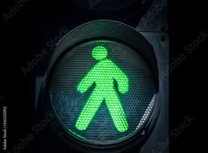 a green pedestrian traffic light with the symbol of a walking man on it at night