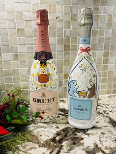 two bottles of wine sitting on top of a counter next to flowers and greenery