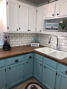 a kitchen with white and blue cabinets and wood counter tops in the corner, along with a black rug on the floor