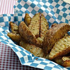 a basket filled with french fries sitting on top of a checkered tablecloth covered table