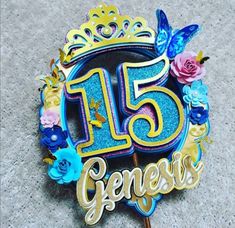 a blue and gold birthday cake with the number fifteen on it's top surrounded by flowers